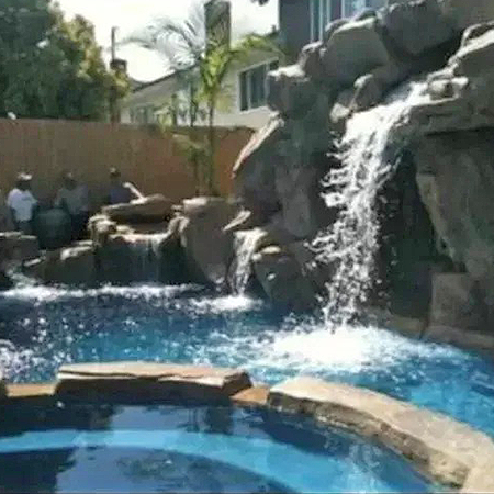 Backyard pool with a rock waterfall and spa