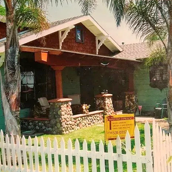 Craftsman bungalow with a river-rock front porch and a Handyman Express yard sign out front
