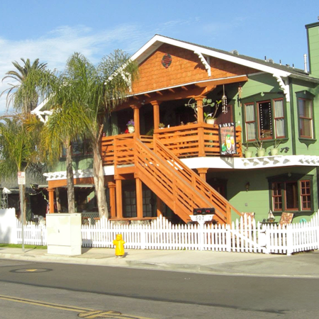 Two-story green Craftsman home with an orange wood exterior staircase and balcony