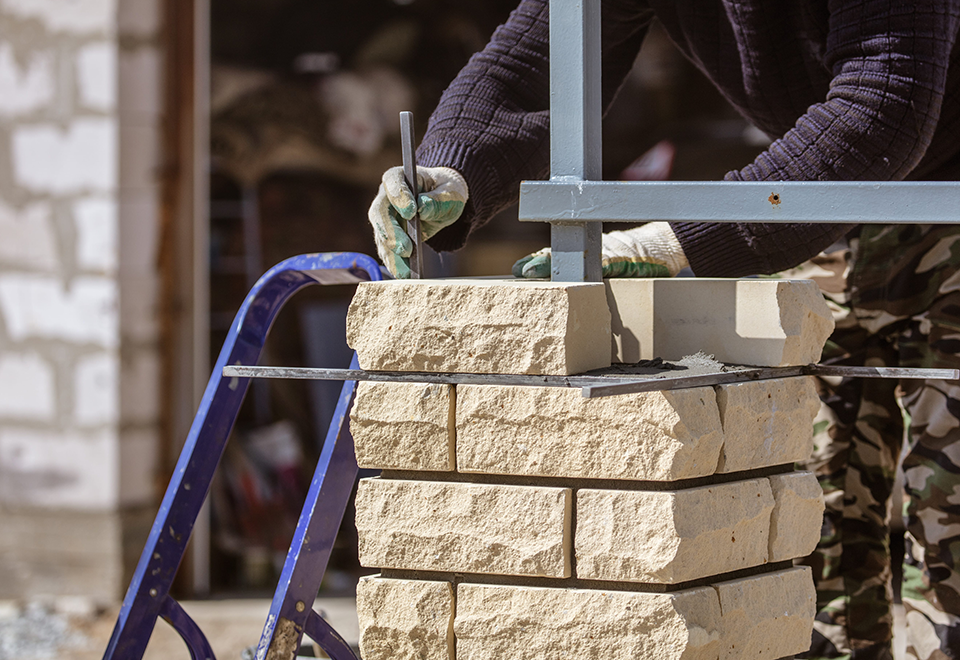 Mason setting stone blocks on a pillar