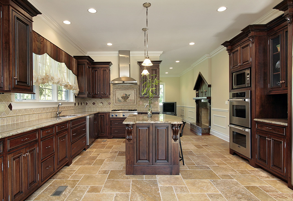 Kitchen with dark cherry raised-panel cabinets, a center island and travertine tile floor