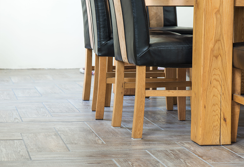 Wood-look ceramic tile floor under a wooden dining table and leather chairs