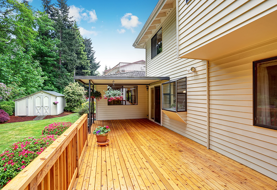 New cedar deck with a wood railing along the back of a house with white siding