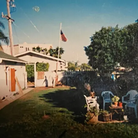 Side yard with a lawn, patio chairs and an American flag beside a house